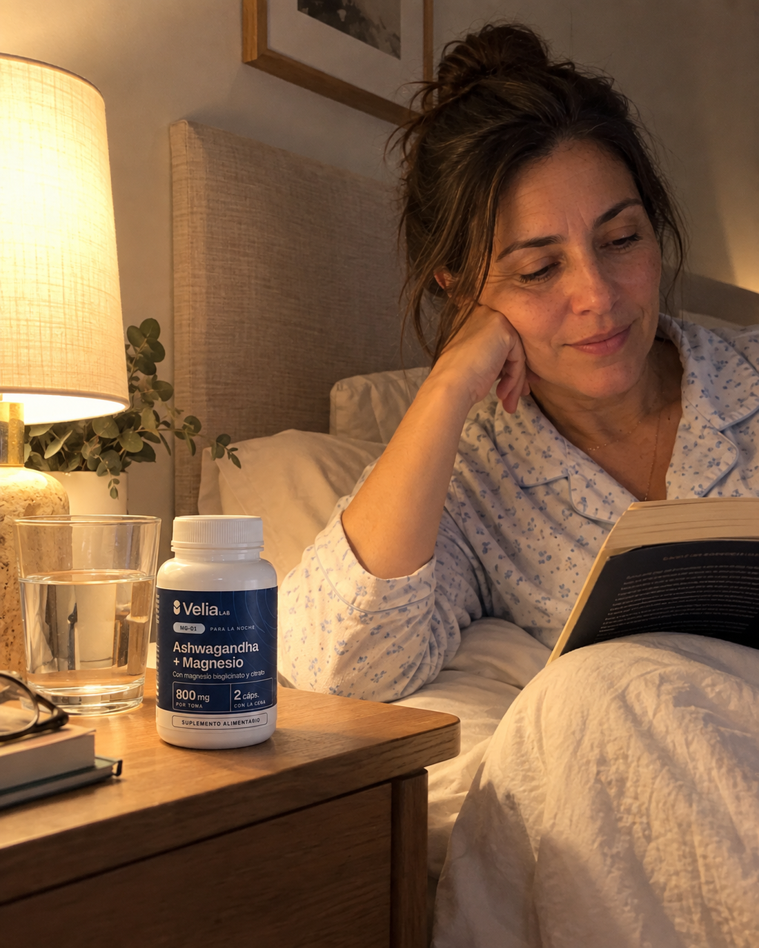 Mujer leyendo en la cama con el frasco MG-01 en el velador
