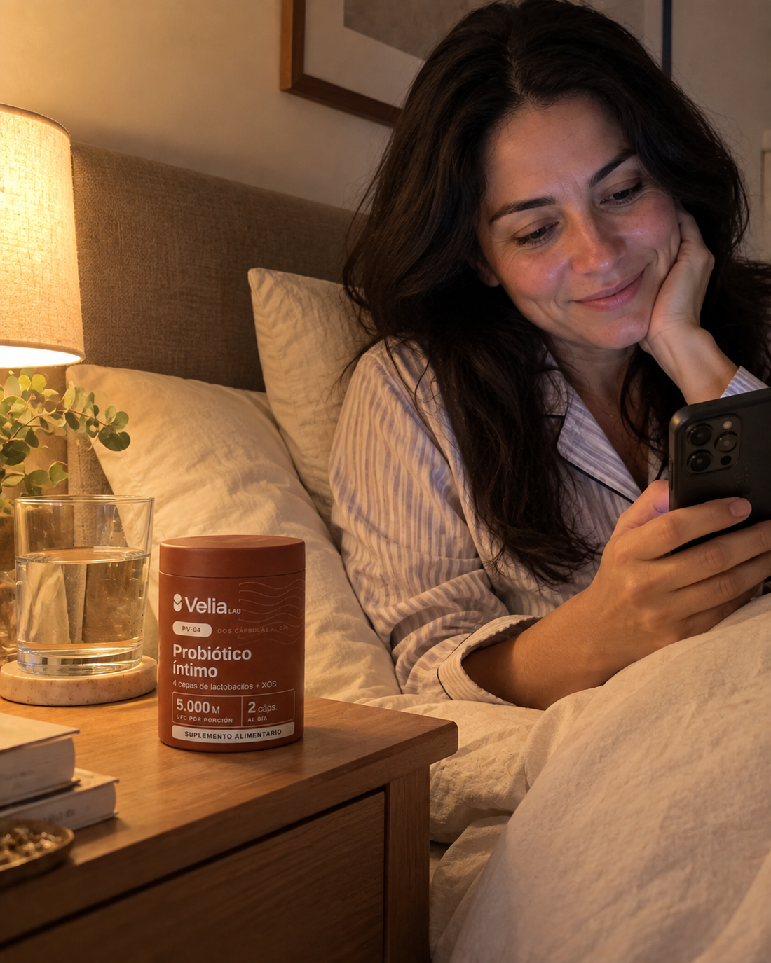 Mujer en la cama mirando el celular, con el pote PV-04 en el velador